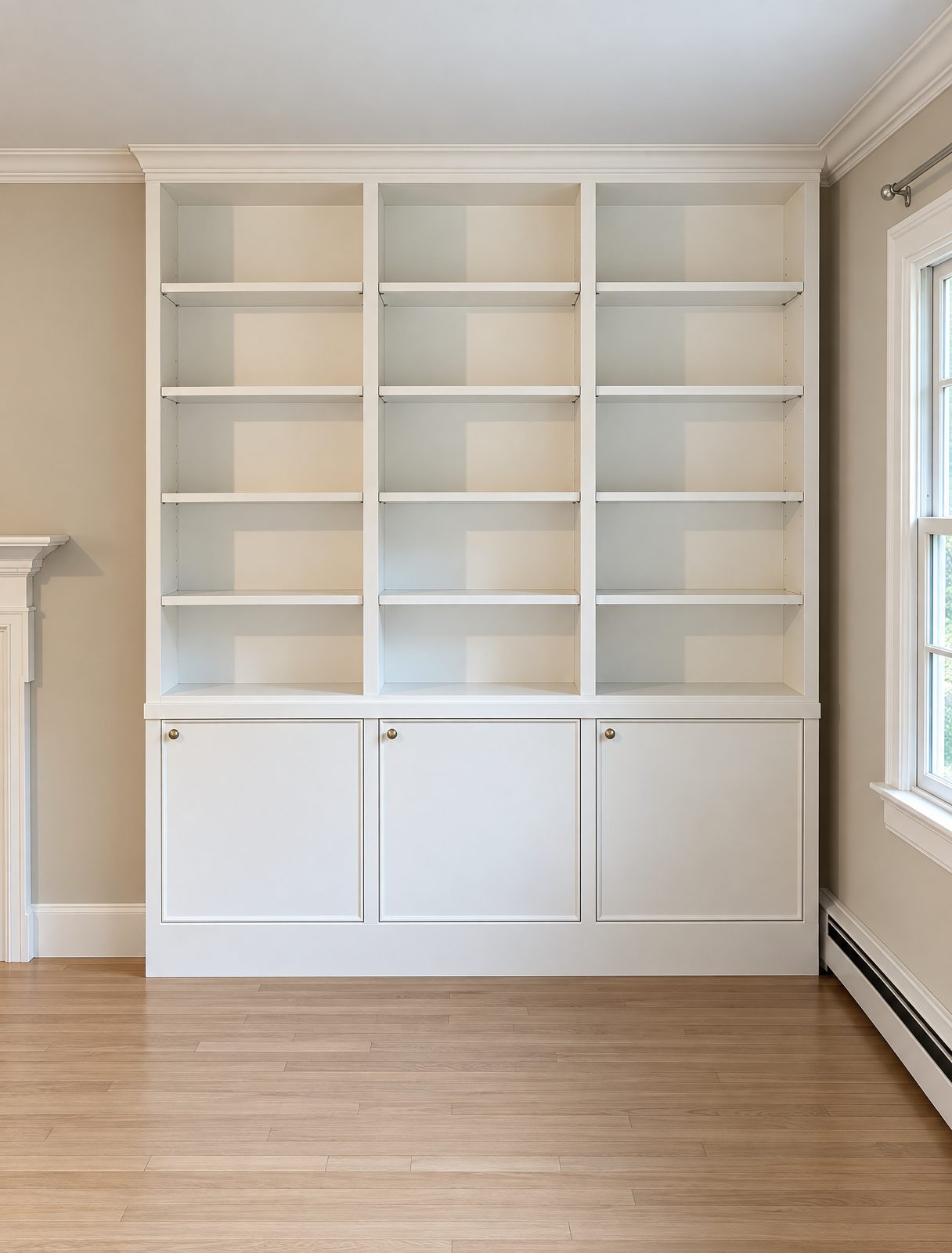 White painted bookcase wall with adjustable shelves above three cabinets