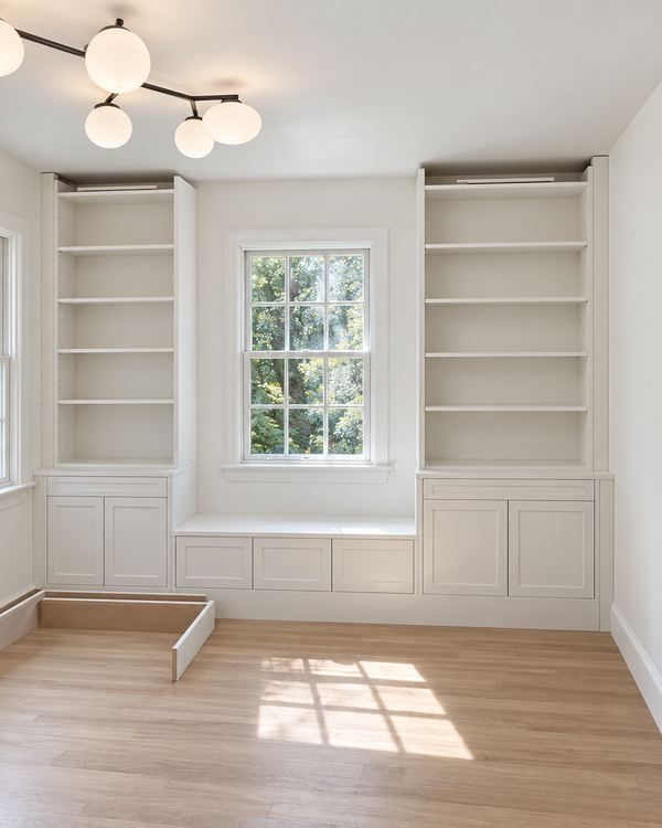 White built-in bookcases flanking a window seat with drawers below