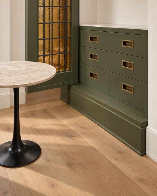 Dressing room cabinetry shown in olive green, with recessed brass pulls beside a glass-paneled door