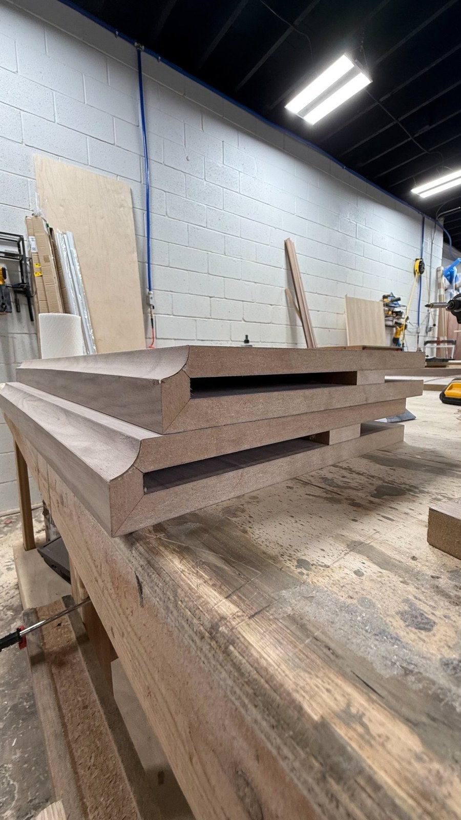 Walnut crown moulding stock stacked on a bench in the épure millwork shop in Little Falls